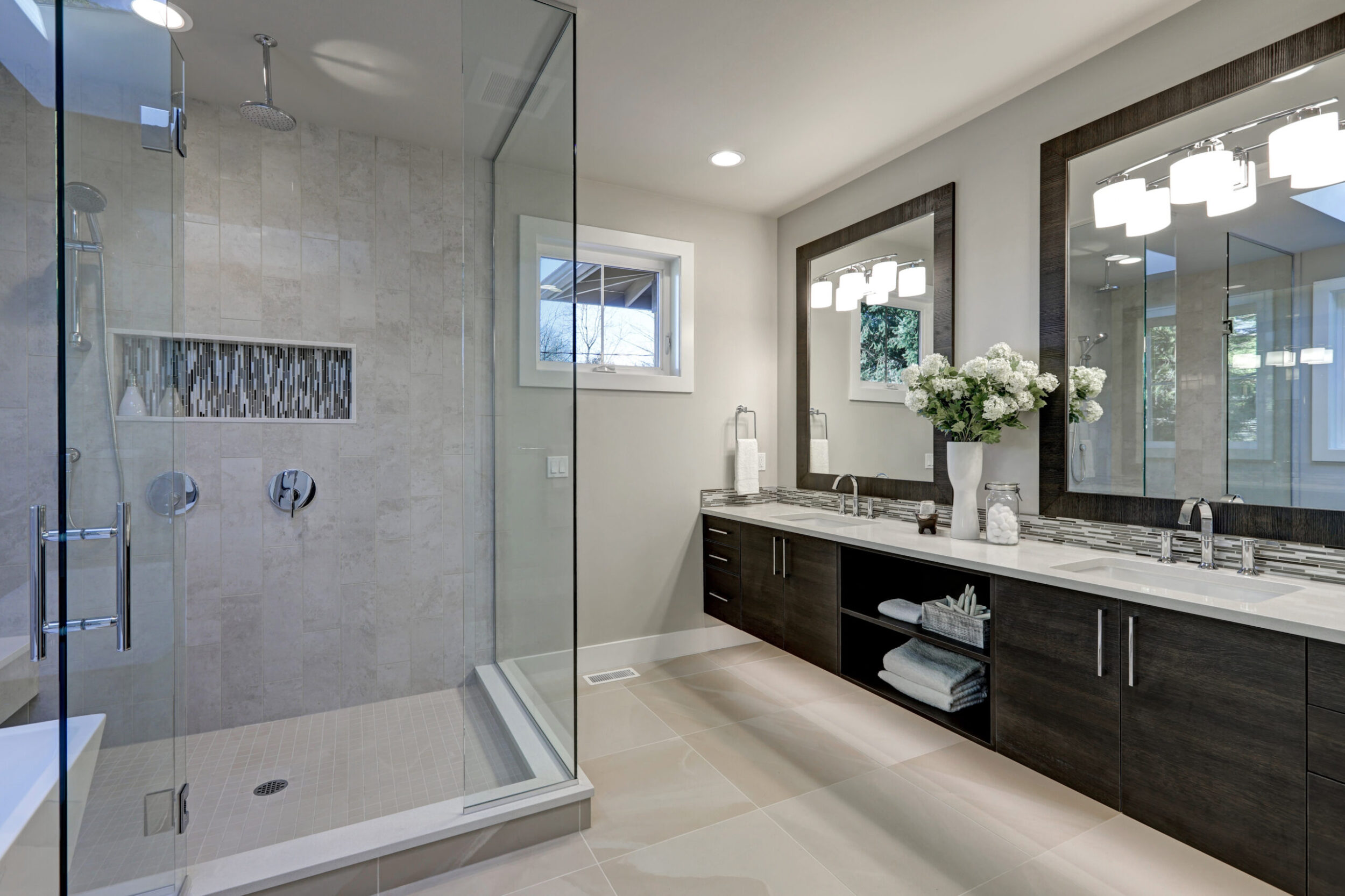 Modern bathroom with glass shower and dual sinks.