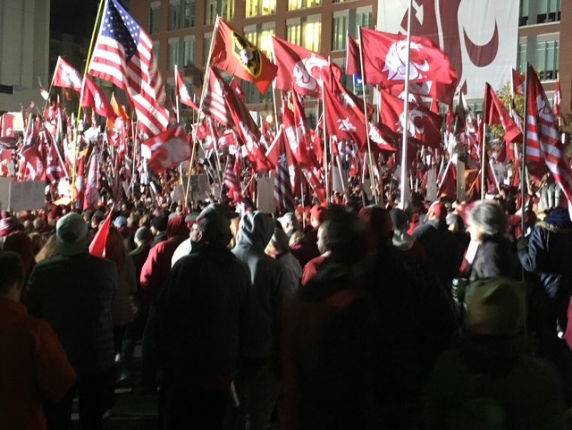 Large nighttime rally with red and American flags