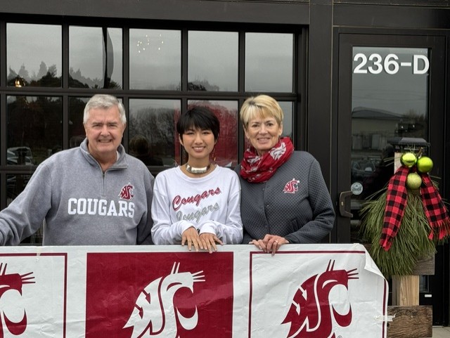 Three people behind Washington State Cougars banner
