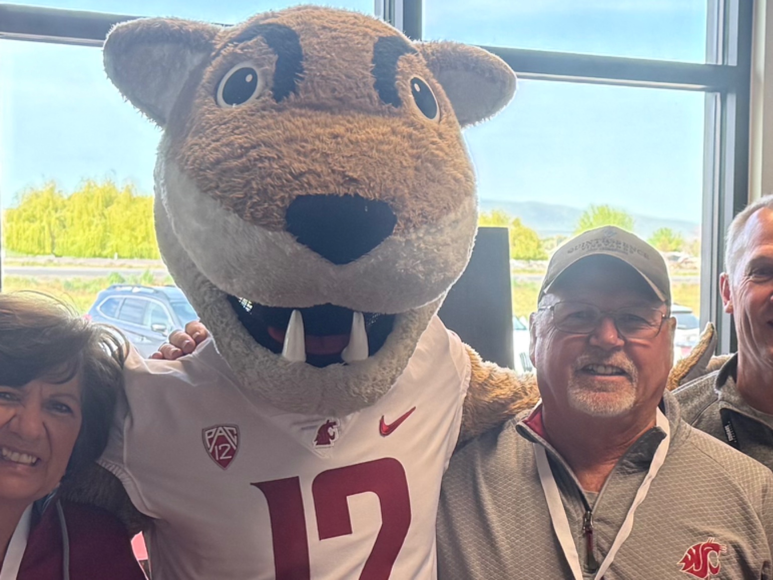 Cougar mascot posing with smiling fans indoors